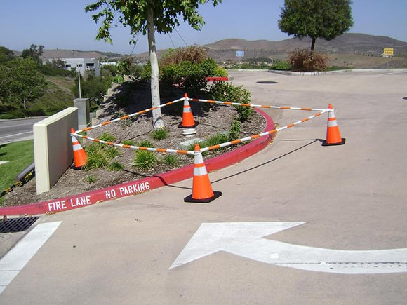 5.5' - 10.5' Orange and White Cone Bars (#150610A-CBOW) with 4x 28" Enviro-Cones cordoning off a section of parking lot landscaping.