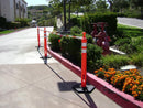 5.5' - 10.5' Orange and White Cone Bars (#150610A-CBOW) with 3x Grabber-Tube II's cordoning off a section of parking lot landscaping/